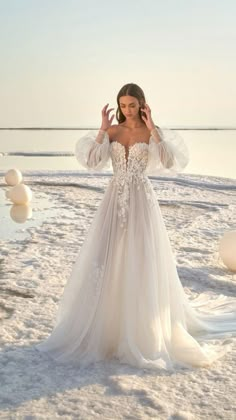 a woman in a wedding dress standing on the beach