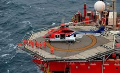 a helicopter is on the deck of an oil rig in the middle of the ocean