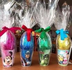 three plastic vases filled with candy and wrapped in cellophane, sitting on a table