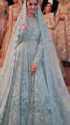 a woman in a blue gown and veil on the runway