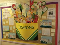 a bulletin board with crayons on it and pictures in the back ground,