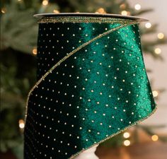 a green lamp shade with gold dots on it and a christmas tree in the background