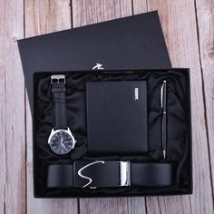 a watch, pen and notebook in a black box on a wooden table with a notepad