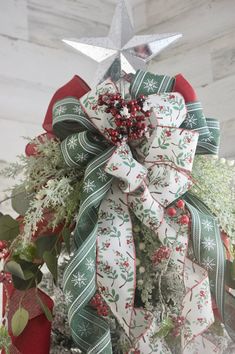 a christmas wreath on top of a tree with a star hanging from the front door