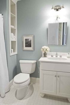 a white toilet sitting next to a sink in a bathroom under a mirror and a shower curtain