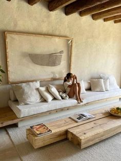 a woman sitting on a white couch in a living room next to a coffee table