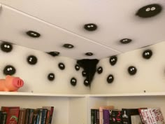 some bookshelves with black and white decorations on the ceiling above them are pig heads