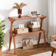 a wooden table sitting next to a window with a vase on top of it and two boxes under the shelf