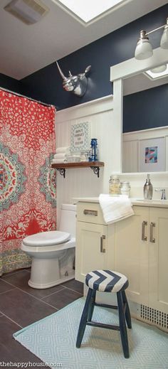 a bathroom with blue and white walls, a red shower curtain and a striped stool