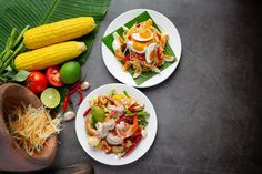 two white plates filled with food next to green leaves