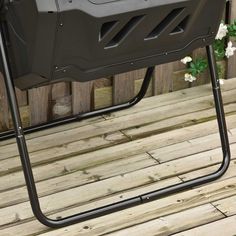 a grill sitting on top of a wooden floor next to a fence with white flowers