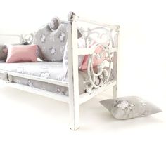 a white daybed with pink and gray pillows on it, next to a pillow case