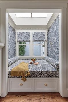 a window seat in the corner of a room with blue and white wallpaper on it