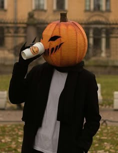 a person in a pumpkin costume drinking from a cup