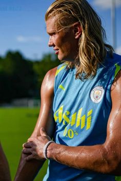 a man with long hair wearing a blue shirt and holding a baseball bat in his hand