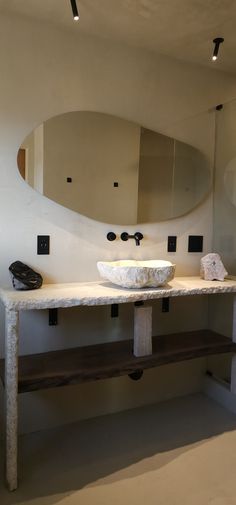 a white sink sitting under a mirror next to a wooden bench