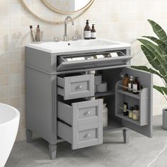 a bathroom vanity with drawers and a sink in the corner next to a potted plant