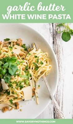 a white plate topped with pasta covered in parmesan cheese and garnished with herbs