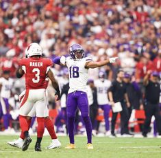 two football players are on the field with their hands in the air and one is pointing