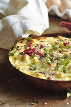 a baked dish with vegetables and herbs on a wooden table