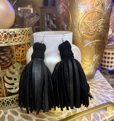 the black tassel earrings are on display next to a vase and other decorative items