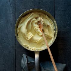 a pan filled with food on top of a wooden table next to a napkin and spoon