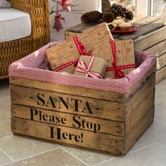 a wooden crate filled with wrapped presents sitting on top of a floor next to a table