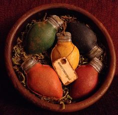 a wooden bowl filled with different types of fruit and wine bottle shaped ornaments on top of grass