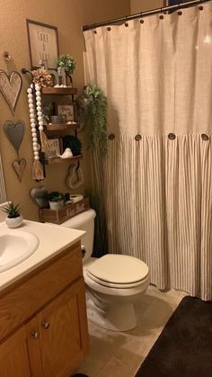 a white toilet sitting next to a bathroom sink under a shower curtain in a bathroom