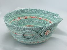 a close up of a bowl on a white surface with a cloth bow in the center