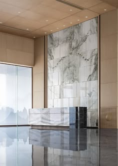 an empty room with marble walls and flooring on the ground, in front of large windows