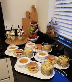 a table topped with plates filled with sandwiches and french fries next to bowls of fruit