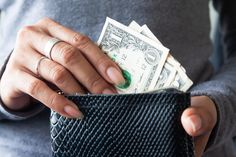 a woman is holding money in her pocket with one hand and two fingers on the other