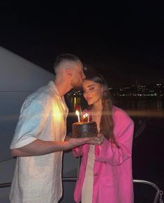 a man and woman standing next to each other with a cake in front of them