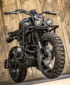 a black motorcycle parked in front of a wooden wall