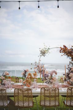 an outdoor table set up with flowers and greenery for a wedding reception by the ocean