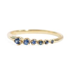 a yellow gold ring with three blue sapphire stones on the side and two small diamonds in the middle