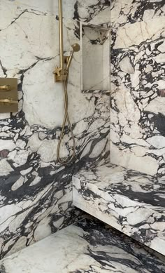 a marble bathroom with a shower head and hand held faucet