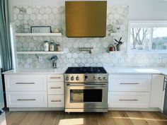 a stove top oven sitting inside of a kitchen next to white cupboards and shelves