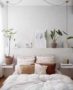 a bed with pillows and blankets on top of it next to a potted plant