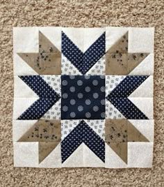 a blue and white quilted star on the ground next to a brown wall hanging