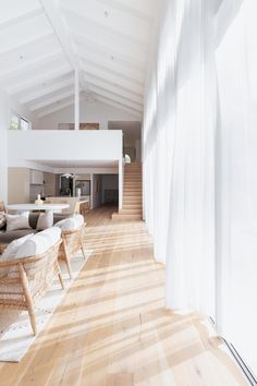 a living room filled with lots of furniture and white walls on top of a hard wood floor