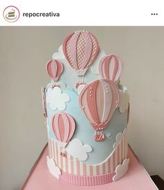 a pink and blue cake with hot air balloons on it