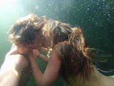 two people are kissing under water in the ocean, with sunlight shining on them and bubbles all around them