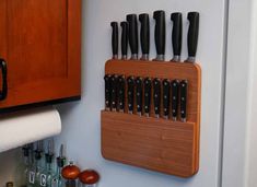 a wooden knife holder with knives hanging on the wall