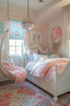 a white bed with pink and blue pillows in a room next to a large window