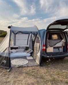 an suv is parked next to a tent with its doors open and it's bed in the back