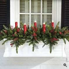 a window sill with candles and greenery