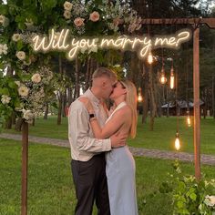 a man and woman kissing under a lit up sign