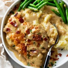 a white plate topped with mashed potatoes and green beans next to gravy